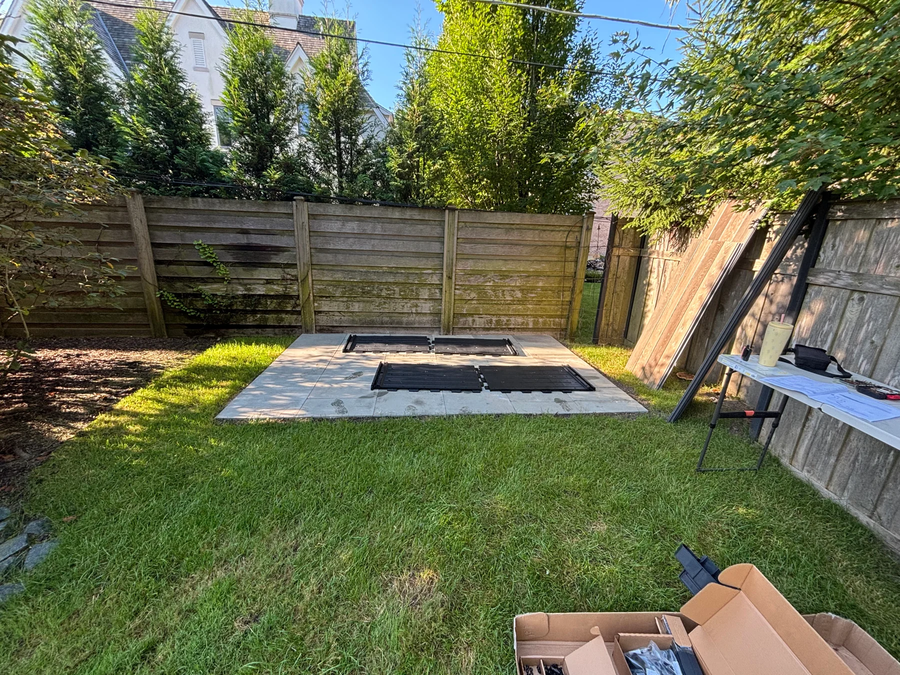 Before assembly: the shed base area in the corner of the yard, with components nearby.