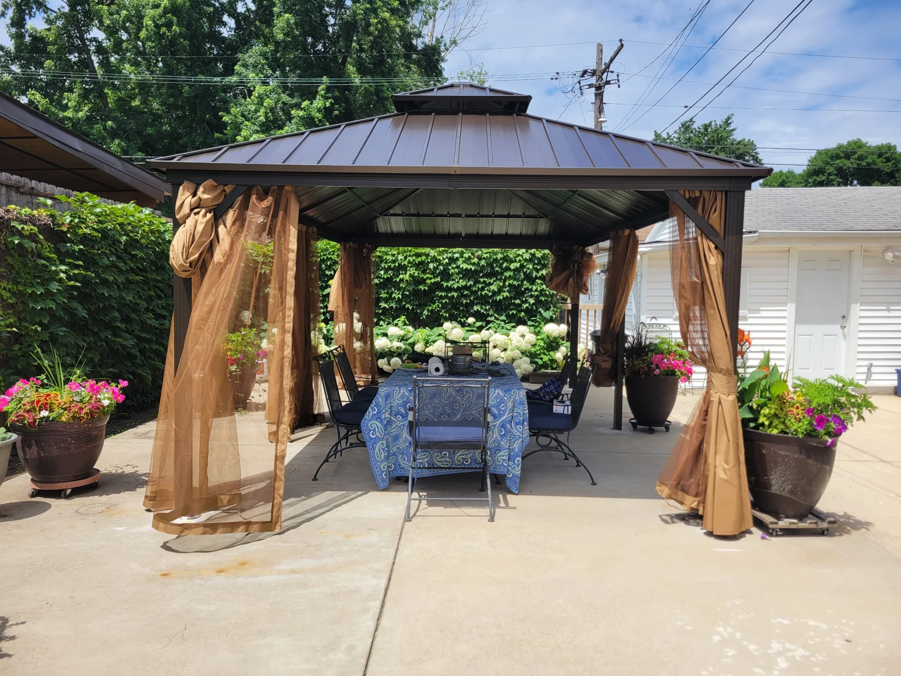 After assembly: a view from the end of the gazebo showing the roof, gathered curtains, and seating beneath the covered structure.