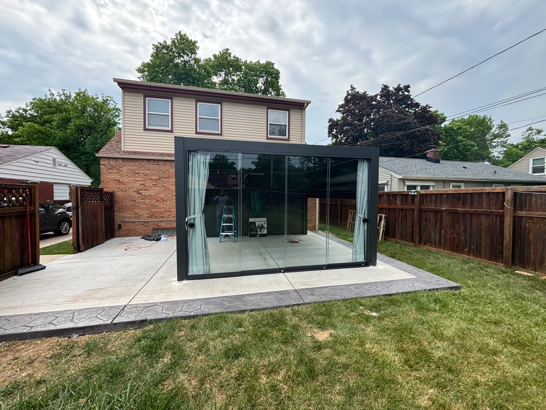 After assembly: a front view showing the sliding glass door panels within the dark pergola frame.