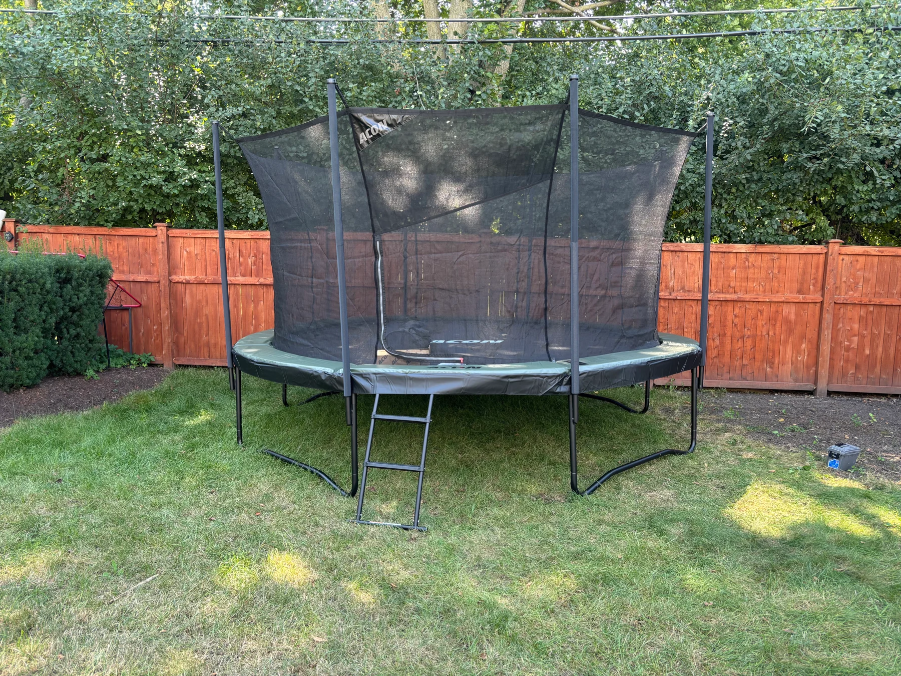 After assembly: the trampoline on the lawn with its enclosure net, frame, and access ladder visible.