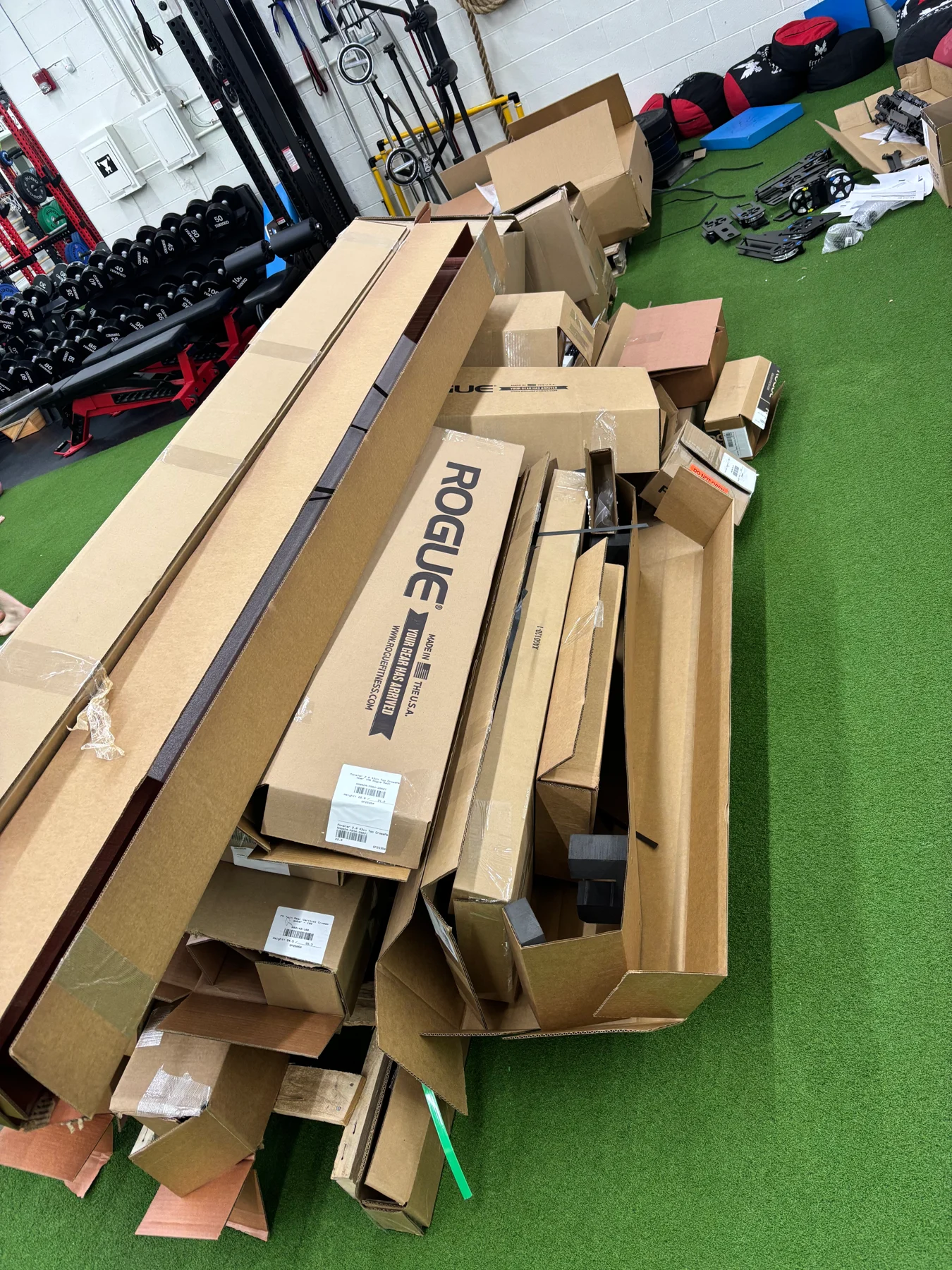 Before assembly: the Rogue delivery boxes and packaged sections in the gym work area.